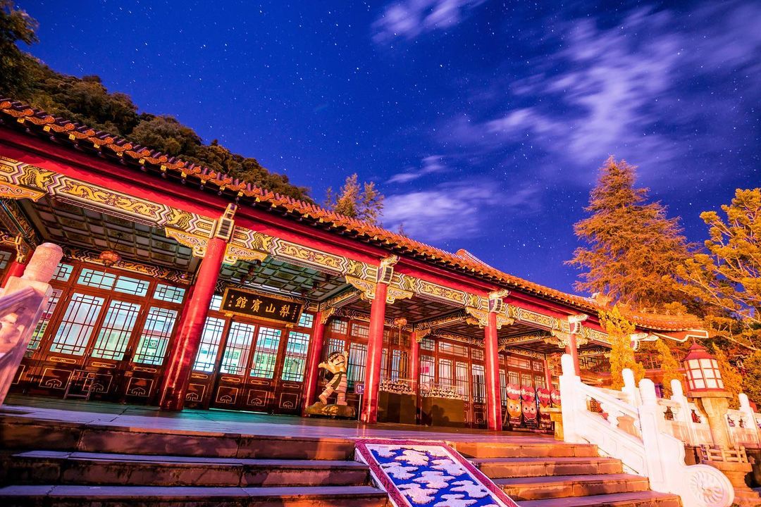 A traditional Chinese building with red pillars and ornate decorations under a starry night sky.