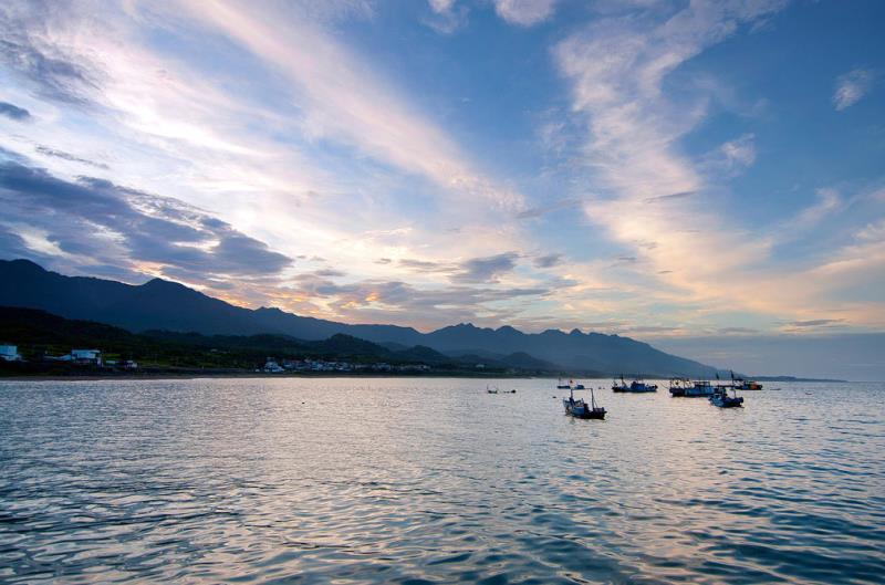 Tranquil seaside at dusk with small boats on calm water