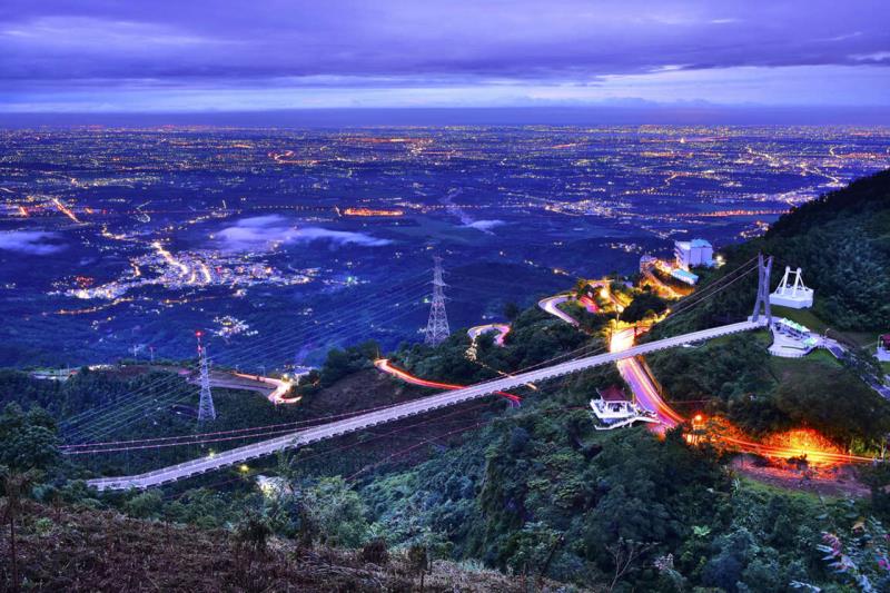 a brightly lit suspension bridge at twilight