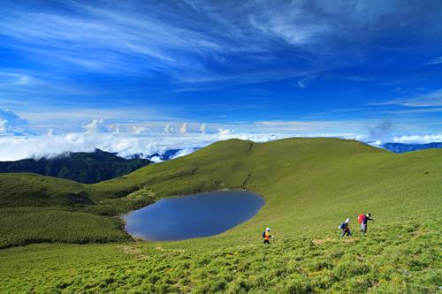 a grassy hill overlooking a serene lake under a vibrant blue sky