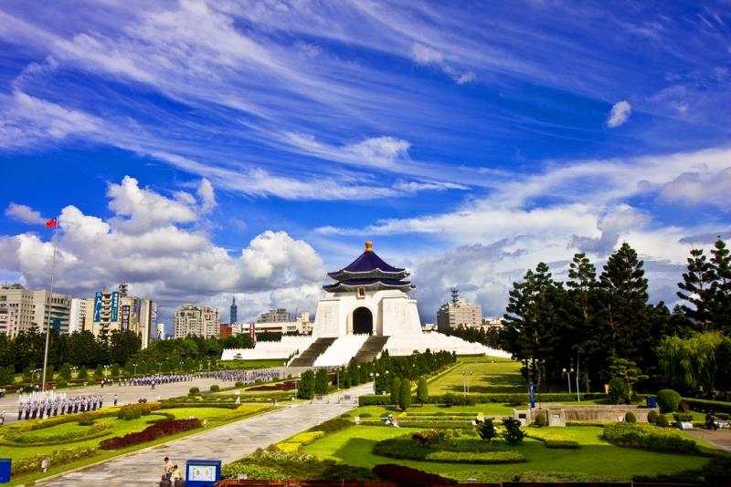 blue sky with wispy clouds over a white memorial hall with a blue roof