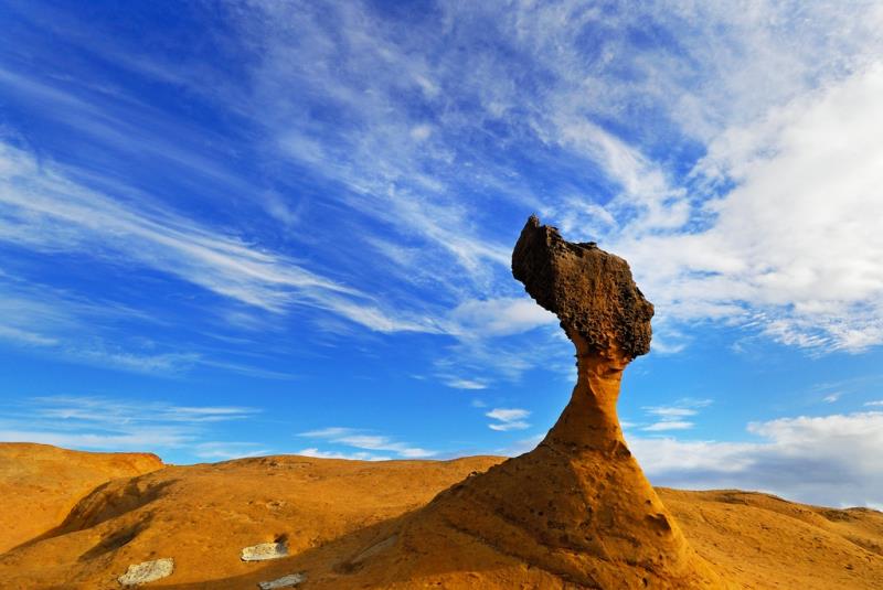 Unique mushroom-shaped rock formation in a golden desert