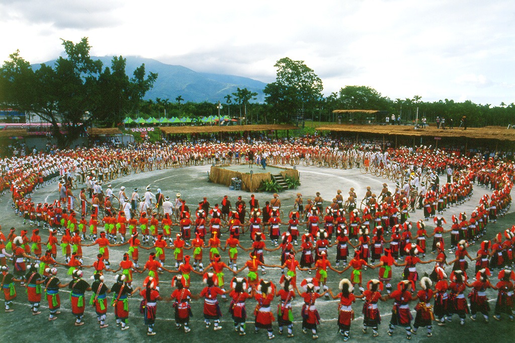 large group of people in traditional red attire forming a concentric circle for an indigenous ceremonial dance